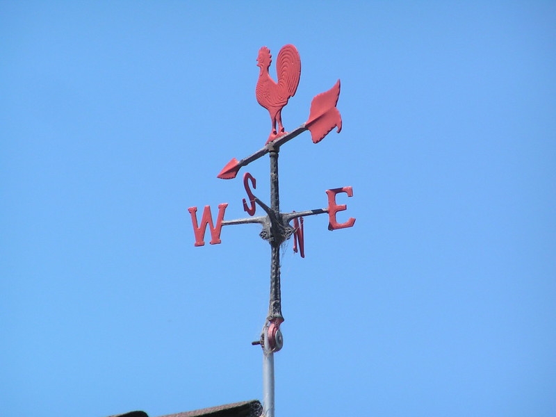 photo of a rooster-topped wind vane with cardinal directions below